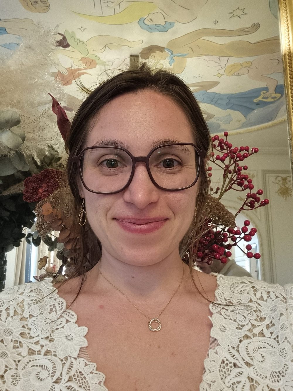 Céline, qui anime les ateliers de punch needle Maison Punch, souriante devant un bouquet de fleurs séchées
