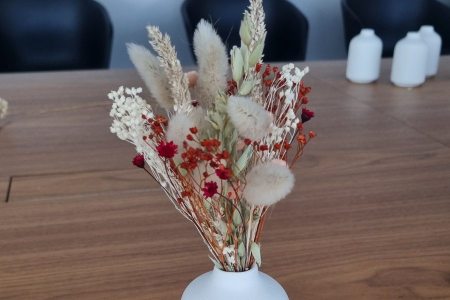 Petit bouquet de fleurs séchées composé en atelier Maison Punch — épis de blé, lagurus, gypsophile et fleurs rouges — dans un vase blanc posé sur une table en bois