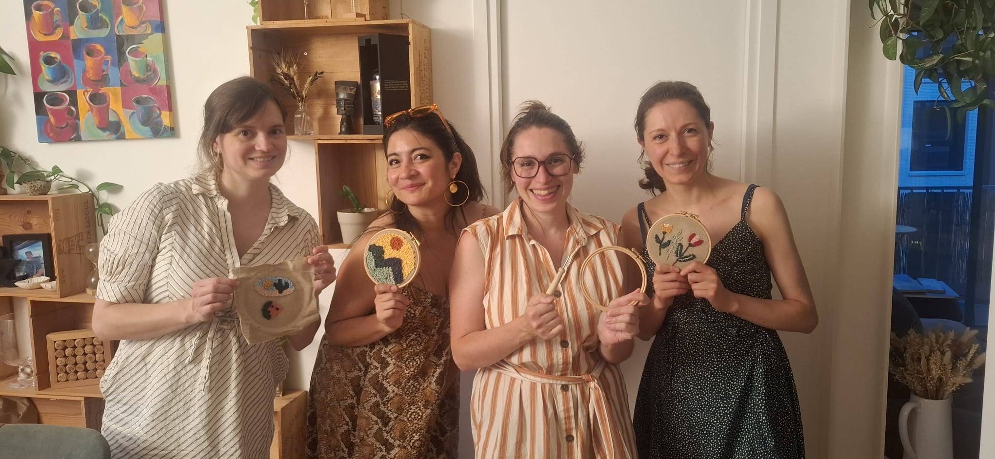 Trois participantes d'un atelier de punch needle à Paris montrent en souriant les tambours qu'elles viennent de terminer