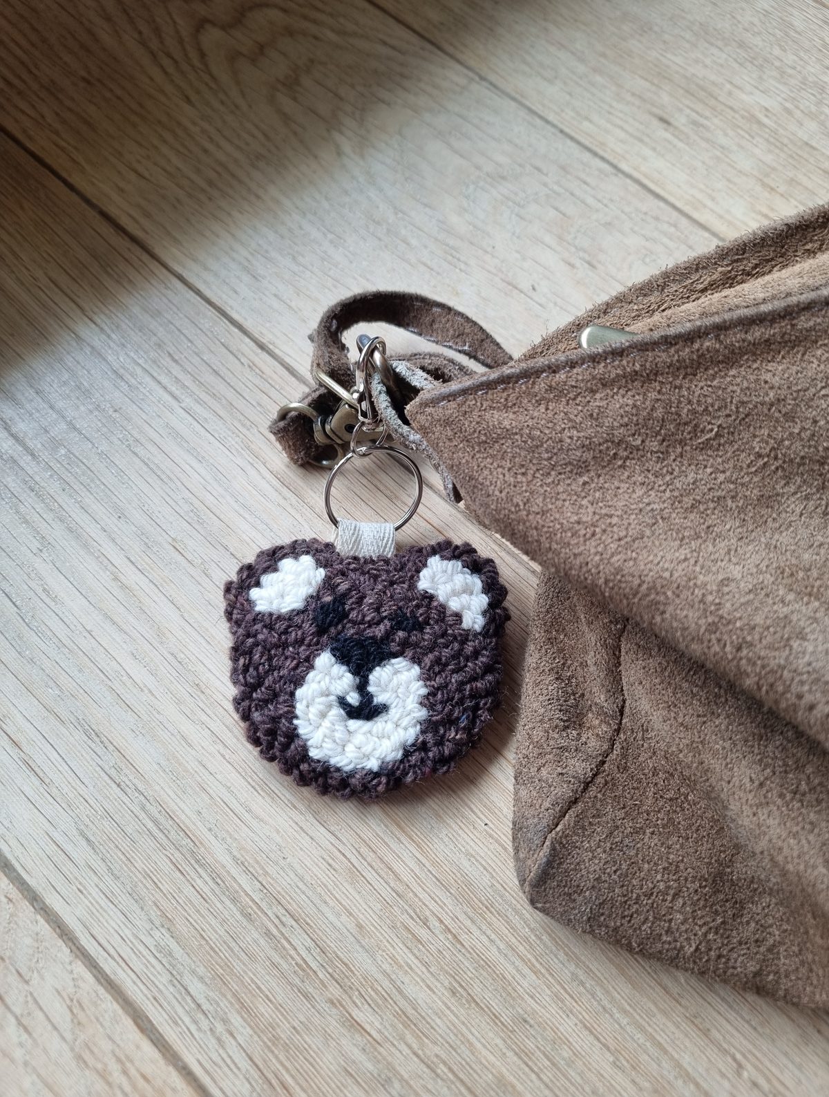 Porte-clef tête d'ours en punch needle accroché à un sac, réalisation de l'atelier parent-enfant