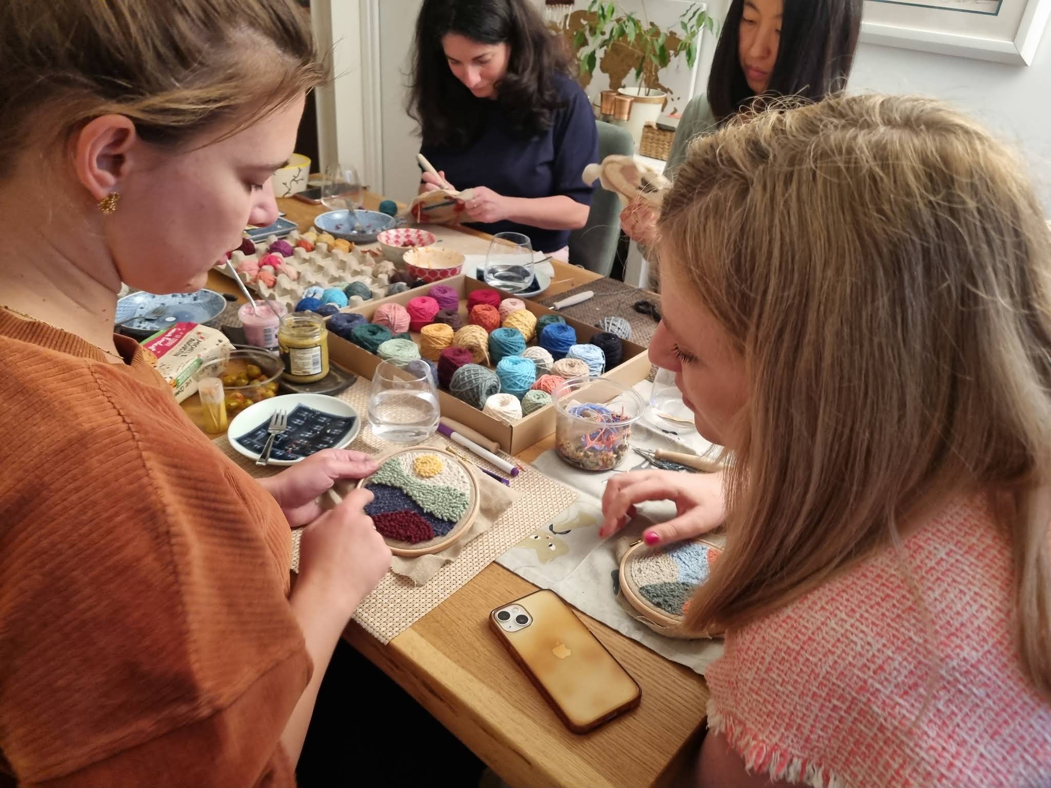 La grande table de l'atelier de punch needle à Paris 11e : toiles tendues, tambours et boîte de laines